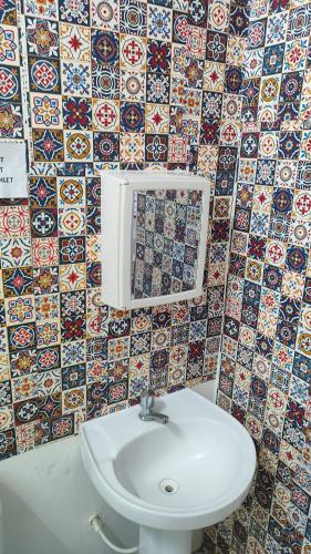 a bathroom with a white sink and a tile wall at House of Colors Hotel in Manaus