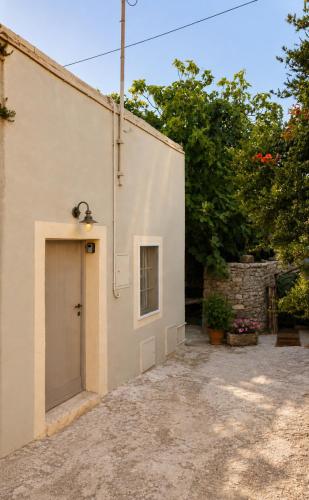 a large white building with a door and trees at Kamara Nest - More than a stay in Aroniadika