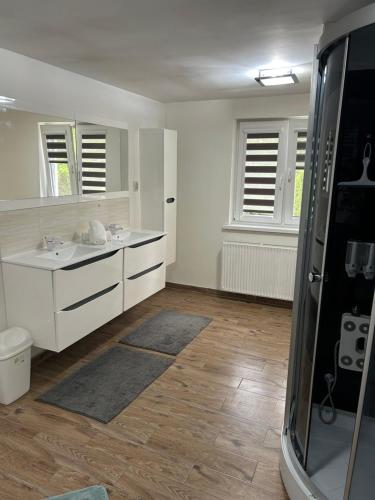 a white bathroom with two sinks and a shower at Pokoje u Niny in Nowe Rumunki