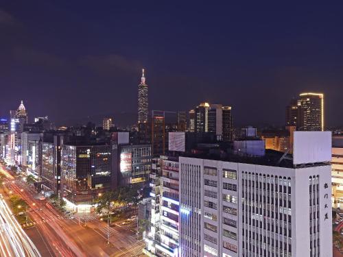 Eastin Taipei Hotel في تايبيه: المدينة مضاءة ليلا بالمباني والزحمة