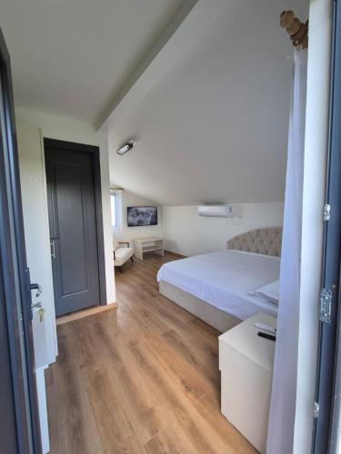a bedroom with a white bed and a wooden floor at Casa LSA in Arefu