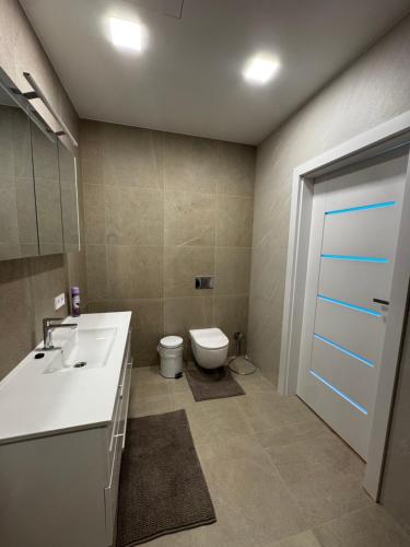 a bathroom with a white sink and a toilet at Apartment in the city center near park and river 26 in Marijampolė