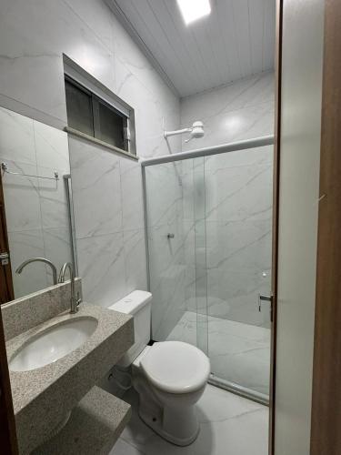a bathroom with a toilet and a glass shower at University Suítes in Carmópolis