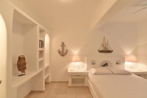 a white bedroom with a bed and a desk at Yria Holiday Home Paros in Márpissa