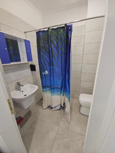 a bathroom with a blue shower curtain and a toilet at Sea&Stay in Shëngjin