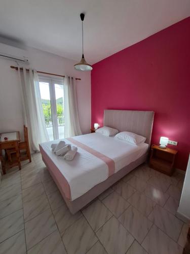 una camera da letto con un letto grande con una parete rosa di Villa Nikitas a Párga