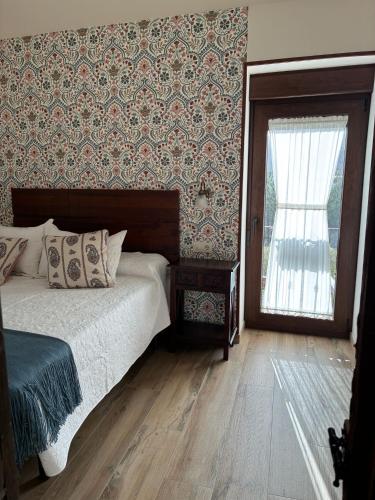 a bedroom with a bed and a window with a curtain at A casiña do Rieiro in San Pelayo
