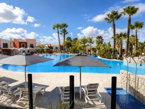 a swimming pool with chairs and umbrellas at a resort at Vila Rio DOuro in Ferragudo