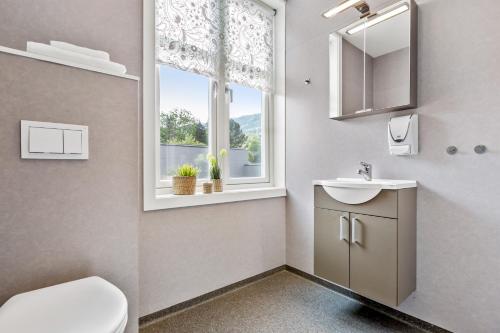 a bathroom with a toilet and a sink and a window at Mogården in Orkanger