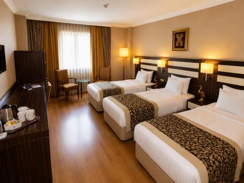 a hotel room with three beds and a table at Akgun Hotel Beyazit in Istanbul