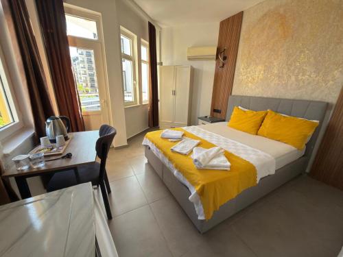 a bedroom with a bed with yellow sheets and a table at FİNİKE SEVER OTEL in Finike