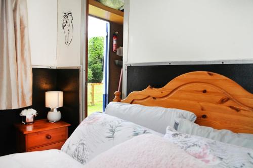 a bedroom with two beds and a wooden headboard at Tarka Trail Horsebox - Hot Tub & Pet proof garden in Littleham
