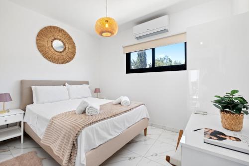 a white bedroom with a bed and a window at Sea Breeze Studios in Pervolia