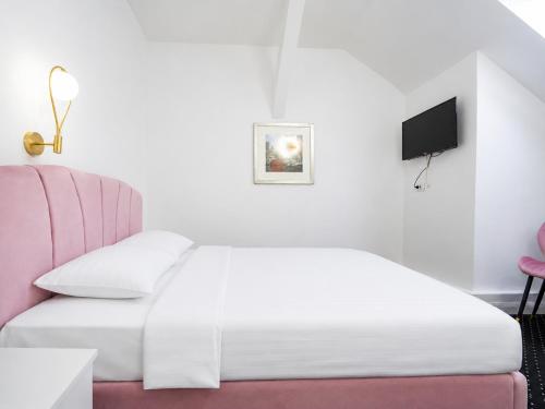 a bedroom with a white bed and a pink chair at Rosetti Inn in Cluj-Napoca
