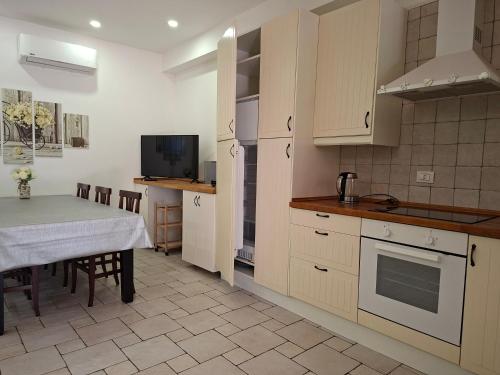 a kitchen with white cabinets and a table and a television at Morrovalle LOVE in Morrovalle