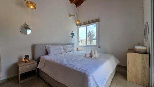 a bedroom with a white bed and a window at Nerina 3 Luxury Villa in Paphos