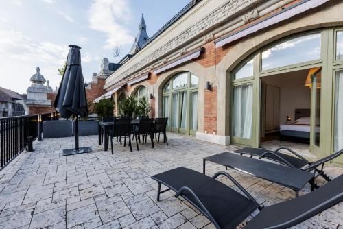 a patio with tables and chairs and an umbrella at Apartments Kozmo Residences Budapest in Budapest