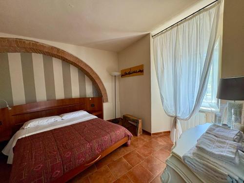 a bedroom with a bed and a table and a window at Appartamento I 2 Archi in Siena