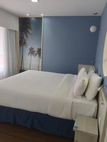 a bedroom with a large bed with white pillows at Apart hotel Mercure boa viagem in Recife