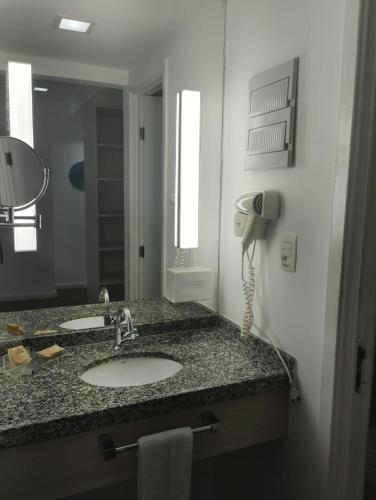 a bathroom counter with a sink and a phone at Apart hotel Mercure boa viagem in Recife
