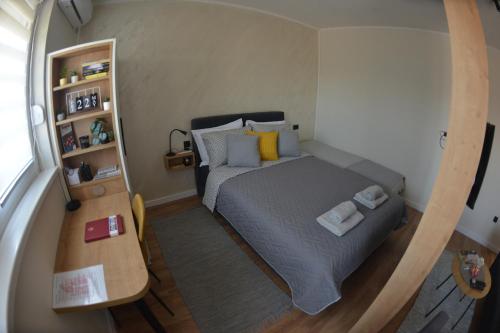 a small bedroom with a bed and a table at Ivy apartman Vršac in Vršac