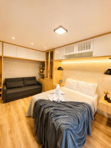 a bedroom with a large bed and a couch at apartamento vitória 101 in Pomerode