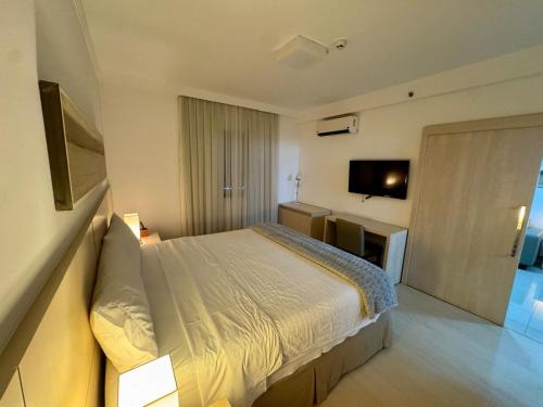 a bedroom with a bed and a flat screen tv at Flat Mont Blanc Premium in Ribeirão Preto