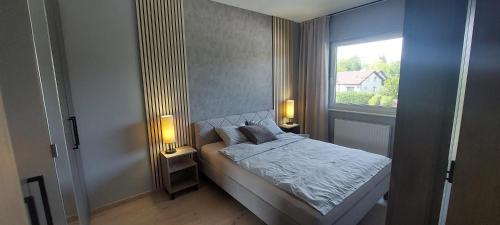 a bedroom with a bed with two lamps and a window at Apartament Podjasnogórski Loretańska in Częstochowa