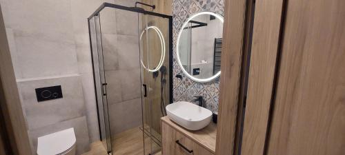 a bathroom with a shower with a sink and a mirror at Apartament Podjasnogórski Loretańska in Częstochowa