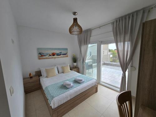 a bedroom with a bed and a large window at Angelo Apartments in Paralía Avdhíron