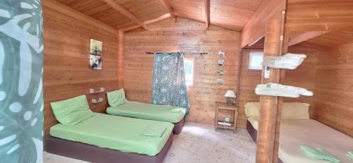 a room with two beds in a wooden cabin at Oasis 56 Aéroport Tontouta in La Tontouta