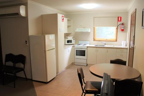 a small kitchen with a table and a white refrigerator at Ballarat Eureka Lodge Motel in Ballarat