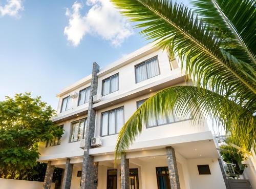a white building with palm trees in front of it at Spacious Pereybere 3BR Apartment in Grand-Baie