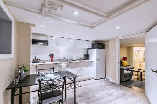 a kitchen with white cabinets and a table and chairs at St Clair Hotel - Cozy Basement Suite with Parking in Toronto