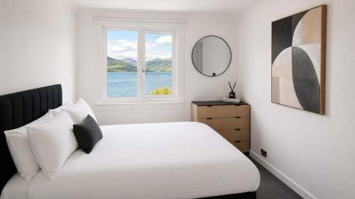 a white bedroom with a bed and a window at Bayview at the Port in Port Bannatyne