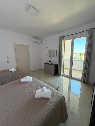 a bedroom with two beds and a large window at Lu Sule lu Mare le Luci in Scorrano