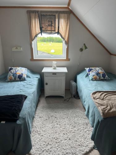 two twin beds in a room with a window at Huset Heimstad i Herfjord in Skippervik
