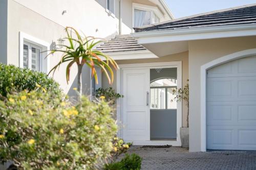 a house with a garage door and a palm tree at Cassa Dunnage At Pezula in Knysna