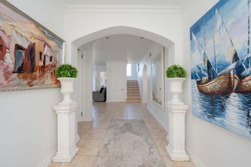 a hallway with white columns and paintings on the walls at Cassa Dunnage At Pezula in Knysna