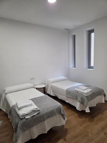 two beds in a room with white walls and wooden floors at Plaza España 2 in Alcazar de San Juan