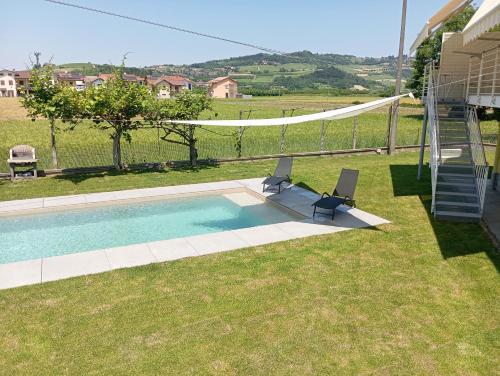 a pool with two chairs and a hammock in a yard at Villa Gemma in Alba