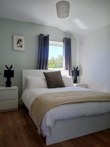 a bedroom with a white bed and a window at Meadow Suite in Lahinch
