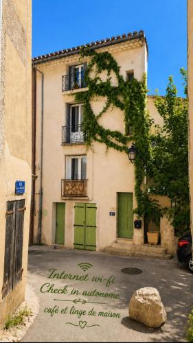 a building with green doors and a sign in front of it at Appartement 2 chambres avec terrasse & parking gratuit Centre Malaucène, Mont Ventoux in Malaucène