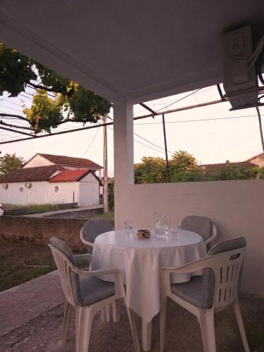 a white table and chairs with a white table and a window at Vikendica Tobi in Čapljina