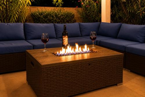 a fire table with two glasses of wine and a bottle of wine at Lighted Pool Nights Fenced Yard & Mountain View in Tucson