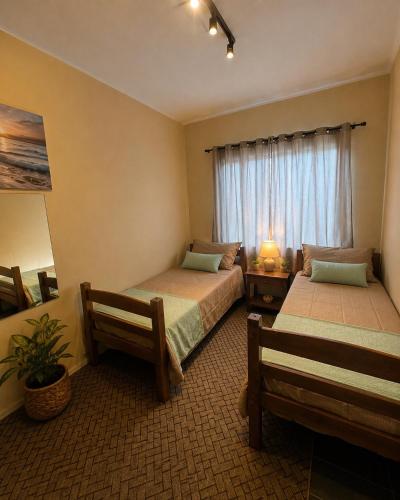 a hotel room with two beds and a window at Pousada Central Araquari in Araquari