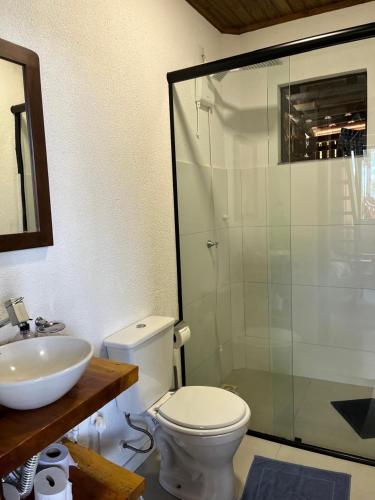 a bathroom with a toilet and a glass shower at Chalé Manacá da Serra in São Bento do Sul