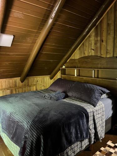 a bed in a room with a wooden ceiling at Chalé Manacá da Serra in São Bento do Sul