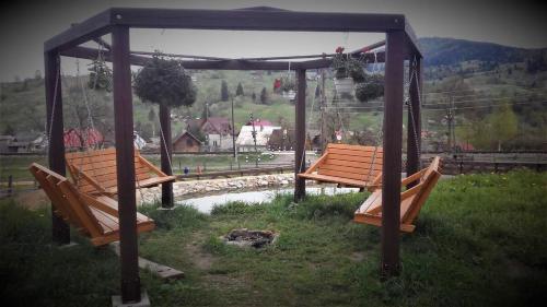 two benches sitting under a gazebo in the grass at Cottage Ozerniy in Lazeshchyna