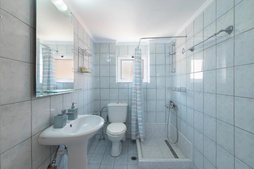 a white bathroom with a toilet and a sink at Rosmaris Apartments in Platanias